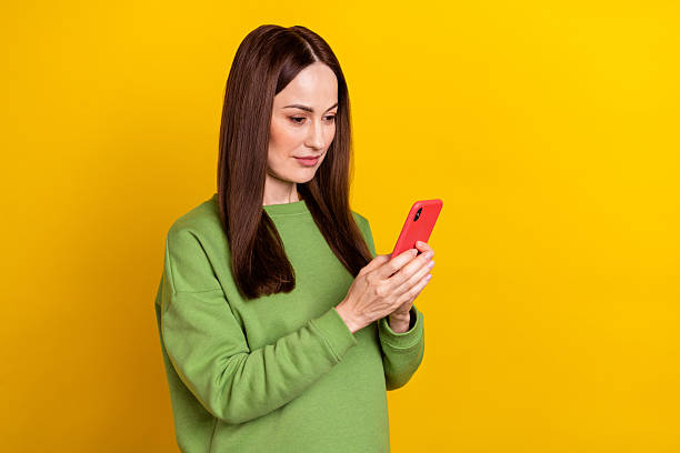 istock Portrait of attractive focused woman using device chatting post smm isolated over bright yellow color background 2207059532