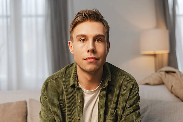 istock Confident young man sitting on comfortable sofa in living room looking at camera 2207060174