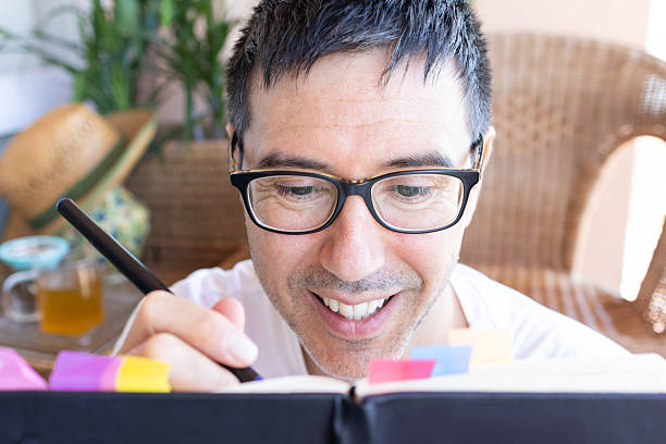 istock Smiling man writing in journal at home 2207060500
