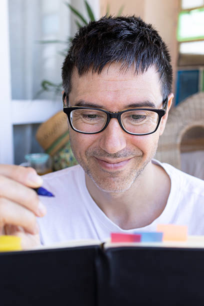 istock Mid adult man writing notes in journal at home 2207060558