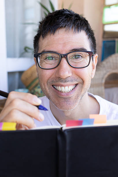 istock Smiling man writing on a journal and looking at camera 2207060584
