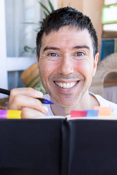 istock Smiling man writing on a journal and looking at camera 2207060610