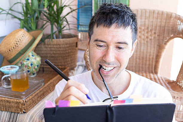 istock Smiling man writing on a journal on a cozy terrace 2207060732