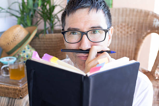 istock Writer smiling and holding pen like a mustache while reading journal 2207061204