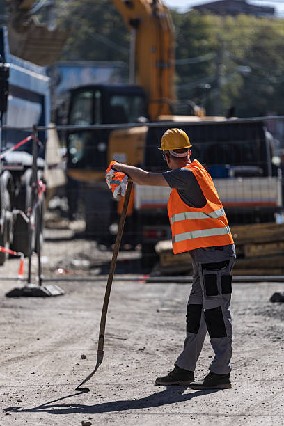 istock Construction worker using a tool for site preparation during the day near heavy machinery and equipment 2207061802