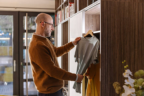 istock Man selecting a shirt from a wardrobe in a modern home interior 2207062133
