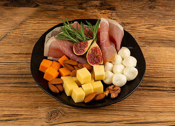 istock Cheese plate with prosciutto, jamon cut, parma ham, serrano slices, cured iberico closeup, cheese board 2207062839