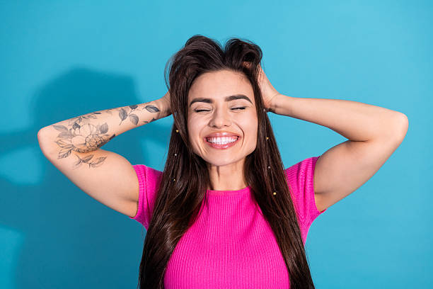 istock Cheerful Young Woman Smiling Brightly Against a Vibrant Blue Background While Posing Playfully in a Casual Pink Top 2207063159