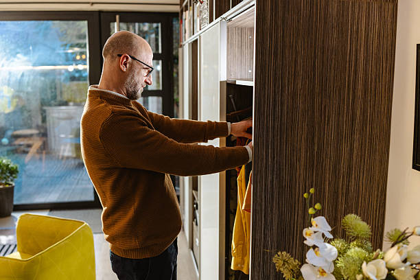 istock Man organizing clothing in a wardrobe in a comfortable home interior space 2207063918