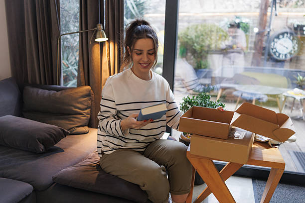 istock Smiling woman unboxing a package at home by a sunlit window 2207063990