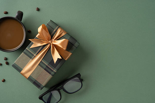 istock Elegant wrapped present with ribbon, sunglasses, and coffee cup on green surface 2207067786