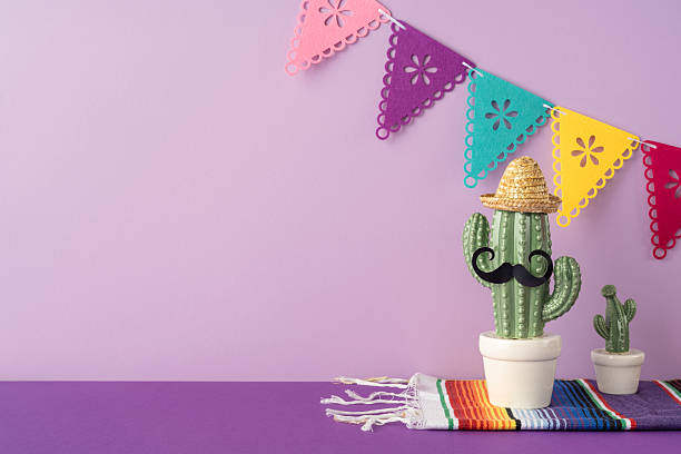 istock A cactus decorated with a sombrero and mustache sitting on a multicolored tablecloth against a purple background with festive papel picado banners adding Mexican cultural charm 2207067789
