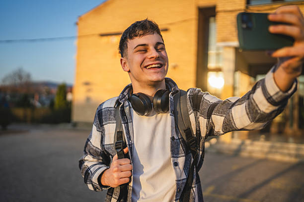 istock man student stand in front university have video call on mobile phone 2207073343