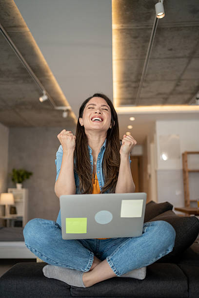 istock Excited young woman celebrating success while working from home 2207074408