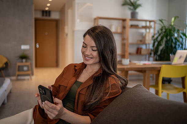 istock Young woman relaxing on sofa using smartphone at home 2207076017
