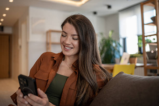 istock Young woman relaxing on sofa using smartphone at home 2207076090