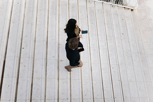 istock Business people walking downstairs while using smartphones 2207078598