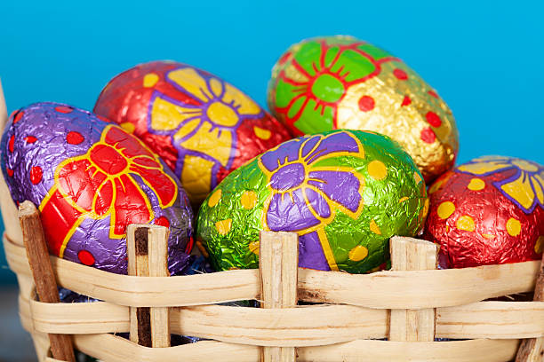 Chocolate easter eggs wrapped in colored foil. All in wooden basket.