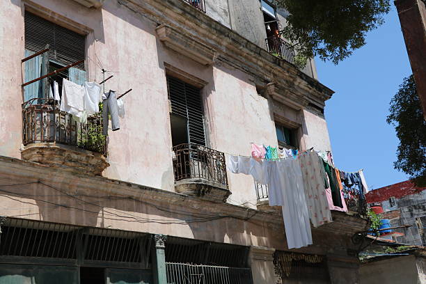 Havana, Cuba - July 15, 2024: Busy balconies on an old weathered building exterior. They have water storage tanks and clotheslines.