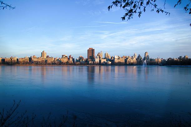 NYC 5th Ave skyline from across a pond, the Jacqueline Kennedy Onassis Reservior, taken near dusk. Taken while walking in Central Park, New York City on a clear winter day.