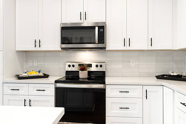 istock A kitchen with stylish white cabinets, a black stove, and microwave 2207089226