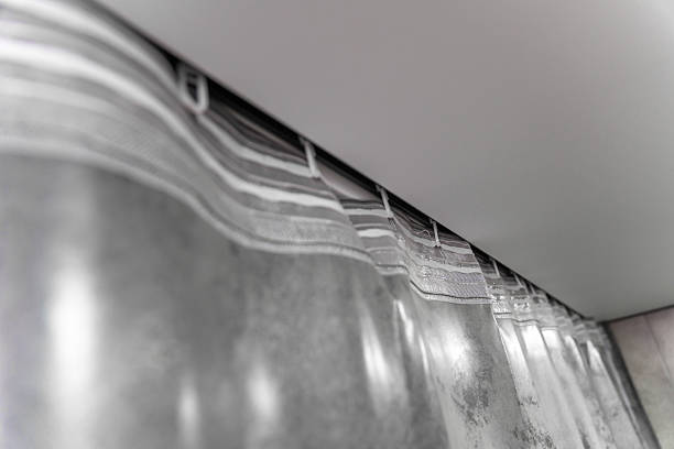 Modern interior design featuring elegant silver curtains hanging from a ceiling-mounted rail, with spotlights providing soft illumination, creating a stylish and contemporary ambiance
