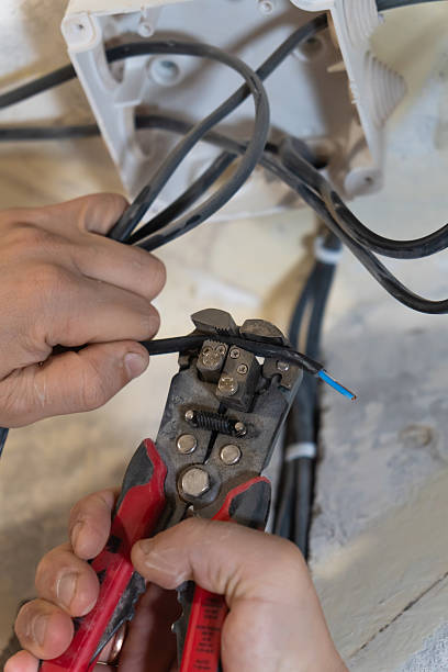 istock Electrician uses wire strippers to carefully remove insulation from an electrical wire, preparing it for connection during a home renovation project. Vertical photo 2207096927