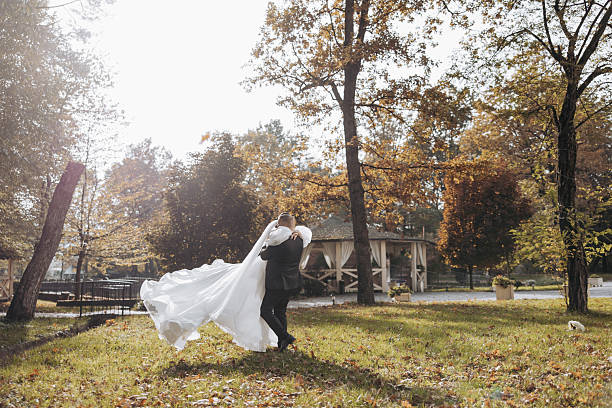 istock A bride and groom are walking through a park 2207098086