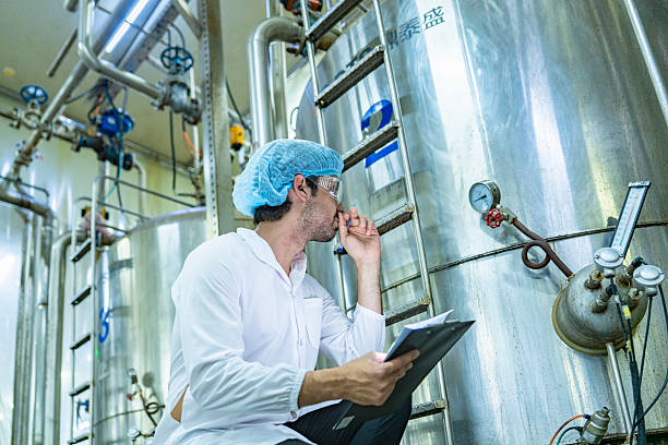 istock Technician in protective gear evaluating a production tank, representing quality assurance, meticulous processes, and expertise in industrial manufacturing. 2207100901
