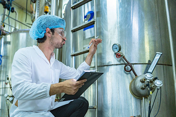 istock Worker examining an industrial tank and recording data on a clipboard, emphasizing the importance of safety, quality assurance, and technological advancement in industrial environments. 2207100969
