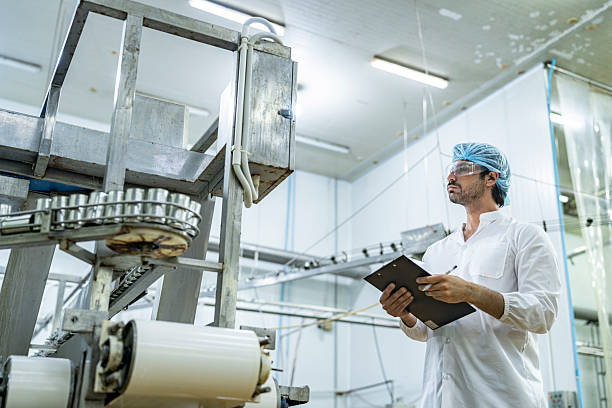 istock Professional quality control scientist inspector examining automated production lines in a modern food manufacturing facility wearing safety gear ensuring hygiene and quality standards compliance. 2207100992