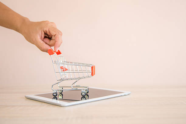 istock Close up the mini shopping cart and notepad at desk concept using the internet application for online shopping buying and spending on computer technology. 2207105422