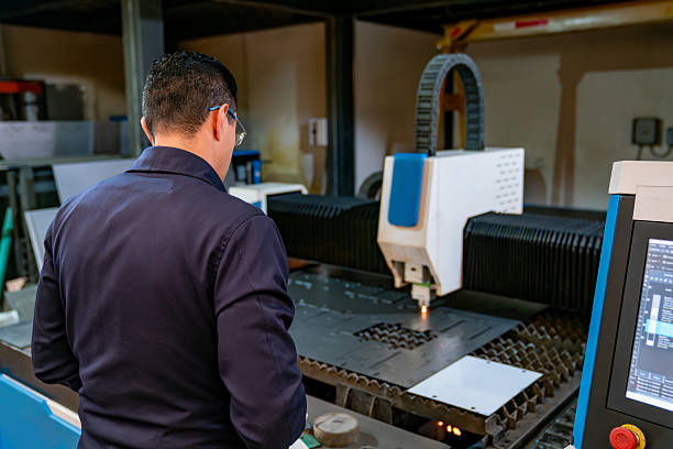 istock Engineer watching a laser machine cutting a metal sheet at a factory 2207107030