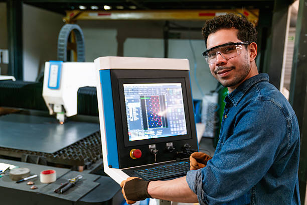 Portrait of a Latin American technician operating a laser cutting machine at a metal factory and looking at the camera