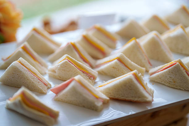Neatly arranged mini ham and cheese sandwiches on a white tray, perfect for events, catering, or buffet-style gatherings.