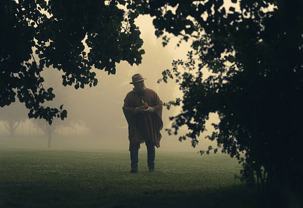 Man wearing a poncho with a yerba matte cup in Misty Rural Field
