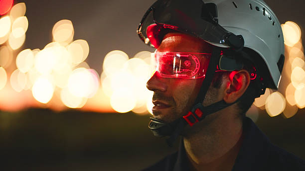istock Young engineer wearing an orange safety jacket and hard hat, working on a clear screen, creating and innovating with graphic input data. 2207113227