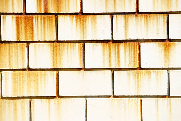 Close-up view of a weathered white brick wall featuring distinct rust stains. This textured background showcases rugged beauty and urban charm.