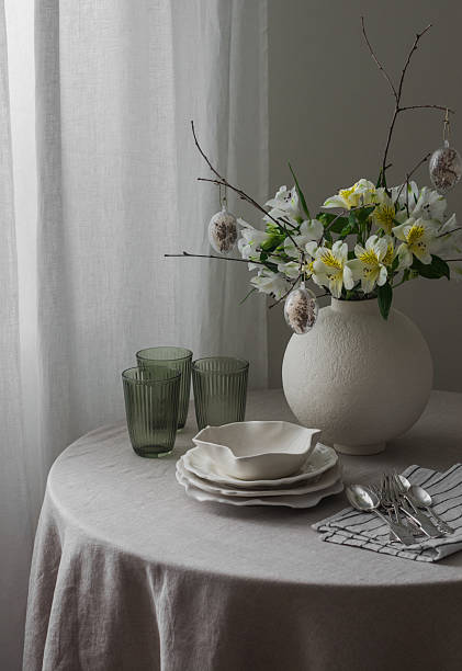 istock Easter table setting - plates, glasses, cutlery, Easter flower arrangement on a round table in the living room. 2207117063