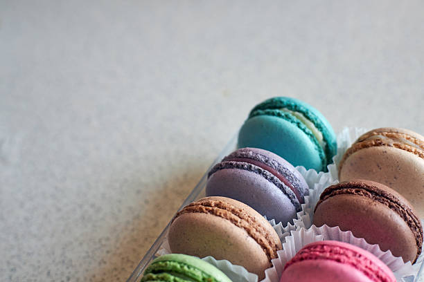 Bright colorful cakes French Macarons with white paperpan in plastic box