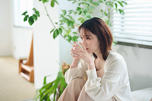 A 20-something woman drinking water in bed