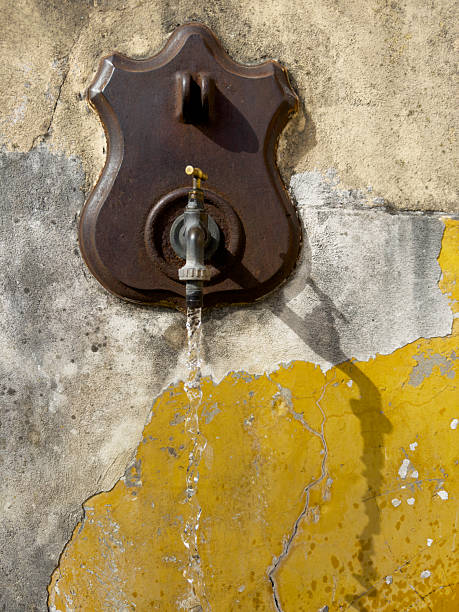istock Rustic Public Fountain with Water Flowing on Yellow Wall. 2207121319