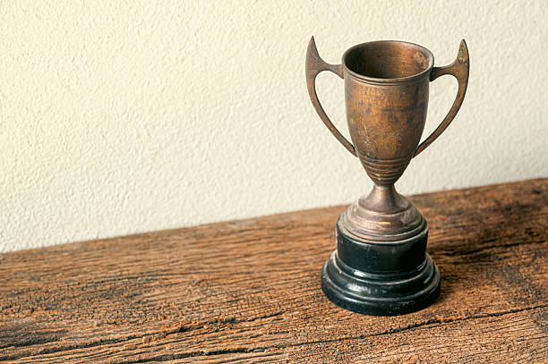 istock Vintage Bronze Trophy on Wooden Table with Neutral Background 2207122214