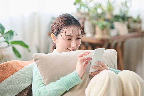 istock A woman relaxing on a sofa while looking at her smartphone 2207122368