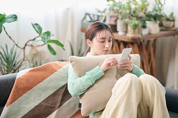 istock A woman relaxing on a sofa while looking at her smartphone 2207122371