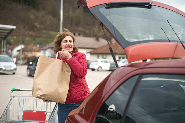 istock Woman put packages in car trunk 2207122936
