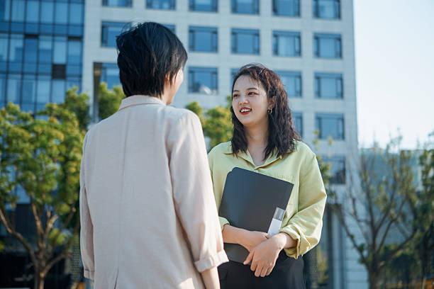 istock Two women holding documents in front of an office building discussing work - collaboration, business, commerce, investment, work, career 2207123376