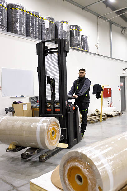 istock Man using forklift for loading bales of electrical insulation tape in distribution warehouse 2207123602