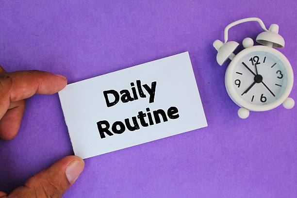 istock an alarm clock and a white paper with the words Daily Routine 2207125270