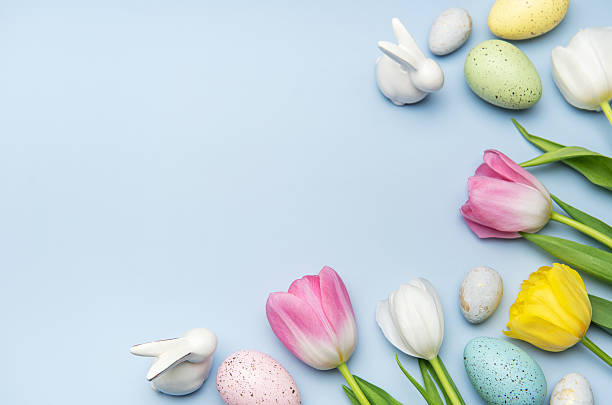 istock Easter eggs and tulips creating a festive border on light blue background 2207126626